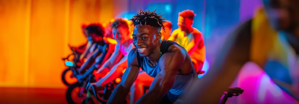 Cyclists in a row participating in the VUSA24 Cycle Challenge with colourful lighting.